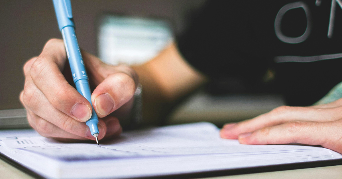 Estudante escrevendo uma carta argumentativa à mão durante preparação para vestibular